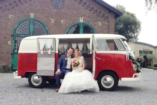 Küssendes Brautpaar im gemietet Oldtimer Hochzeitsauto VW Bulli