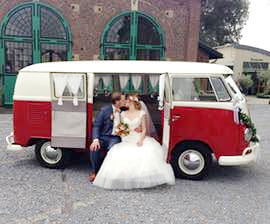 Küssendes Brautpaar im gemietet Oldtimer Hochzeitsauto VW Bulli